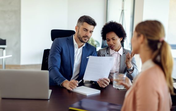 Members of human resource team talking while analyzing resume of a potential candidate during job interview in the office.